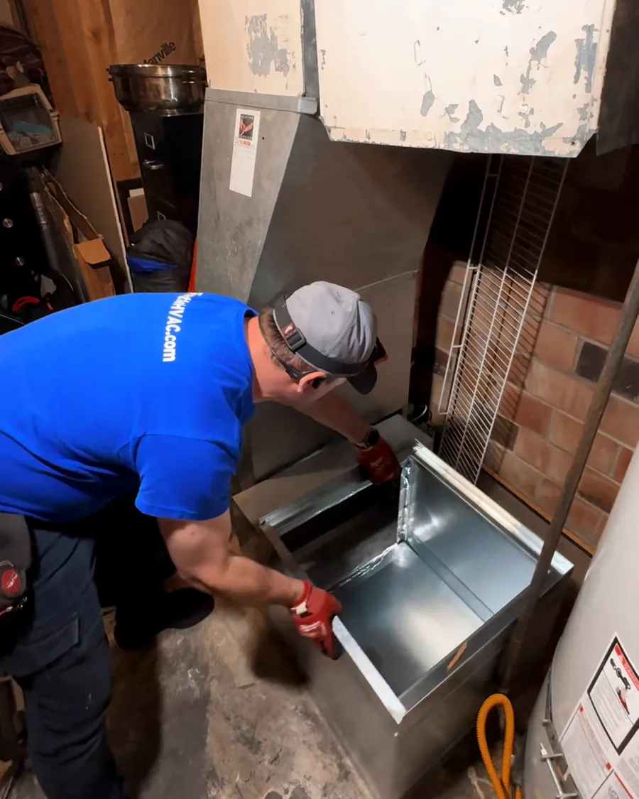 Technician fitting a new sheet-metal base for a furnace replacement