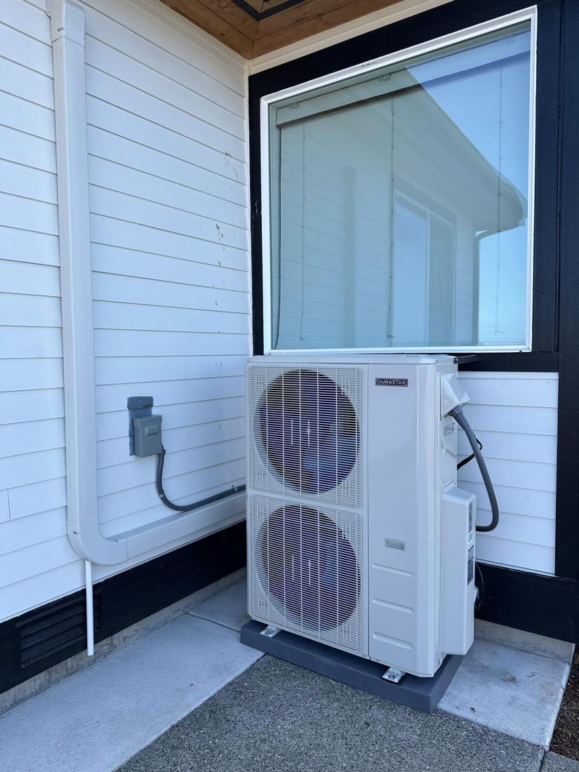 New heat pump on a pad beside a white-sided home