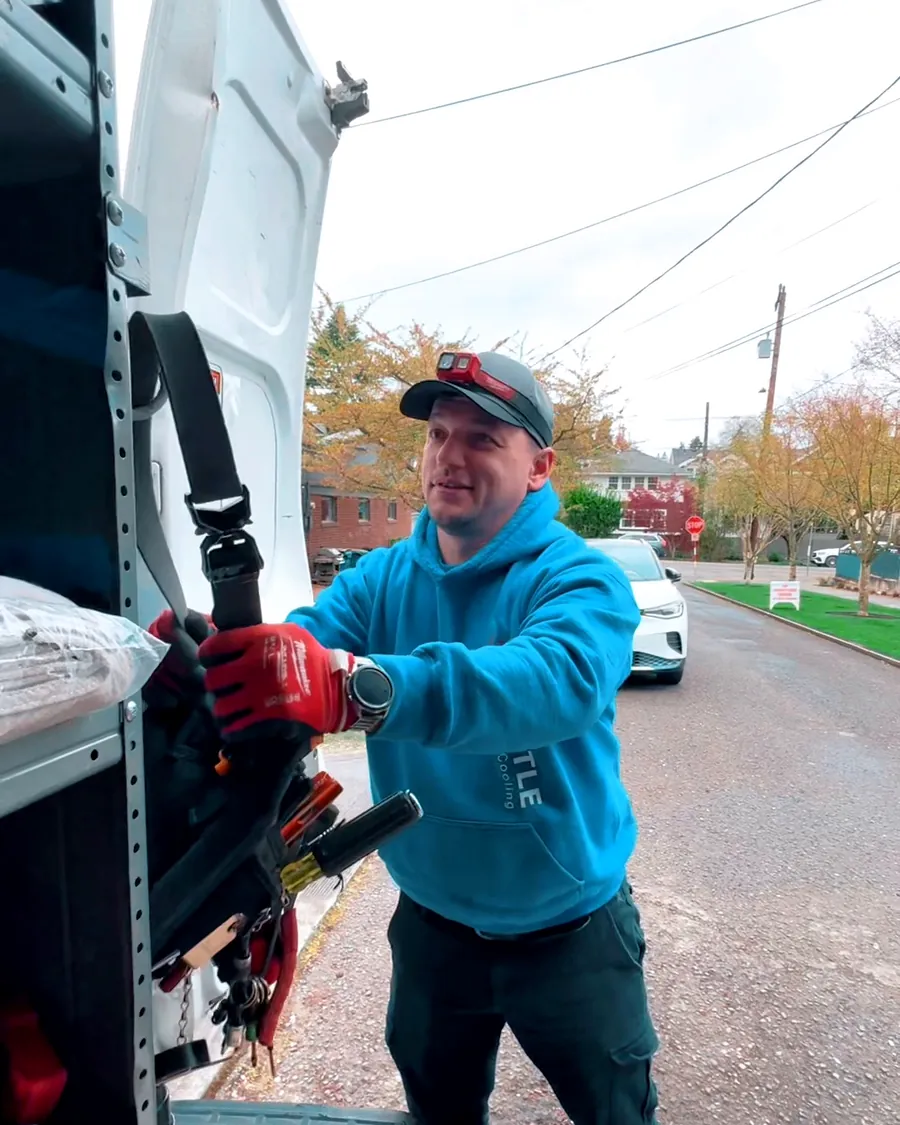 Smiling Seattle Heating & Cooling technician loading tools from the service van