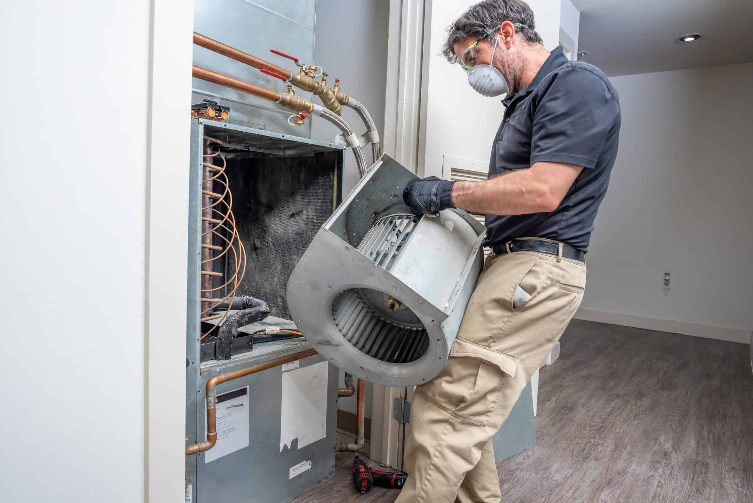 seattle heating cooling kirkland Mini Split System Installation What to Expect When Installing a Mini Split System scaled - Seattle Heating & Cooling A man putting a component into an A/C unit.