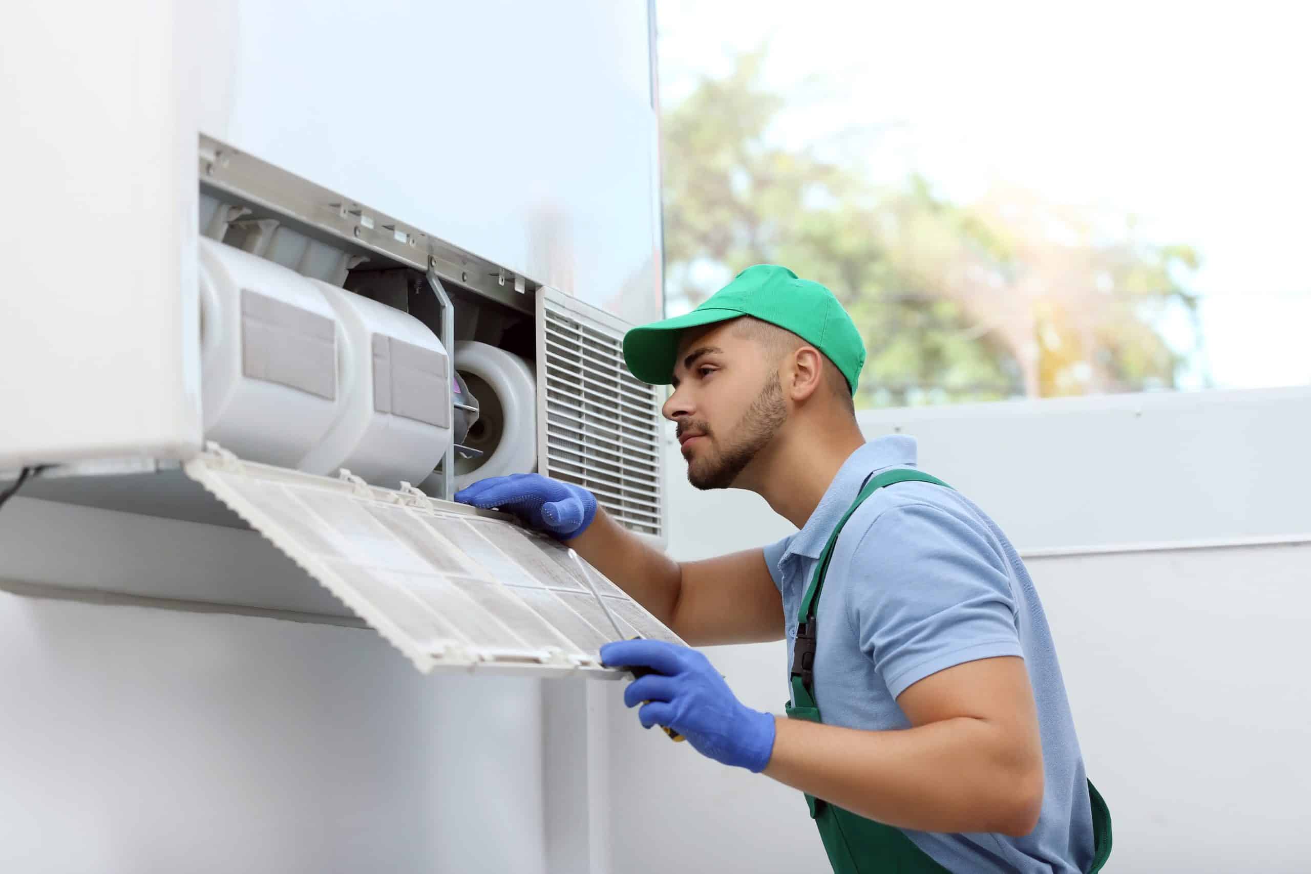 seattle heating cooling lynwood Mini Split System Installation What to Expect When Installing a Mini Split System scaled - Seattle Heating & Cooling A man inspecting an outdoor A/C unit.
