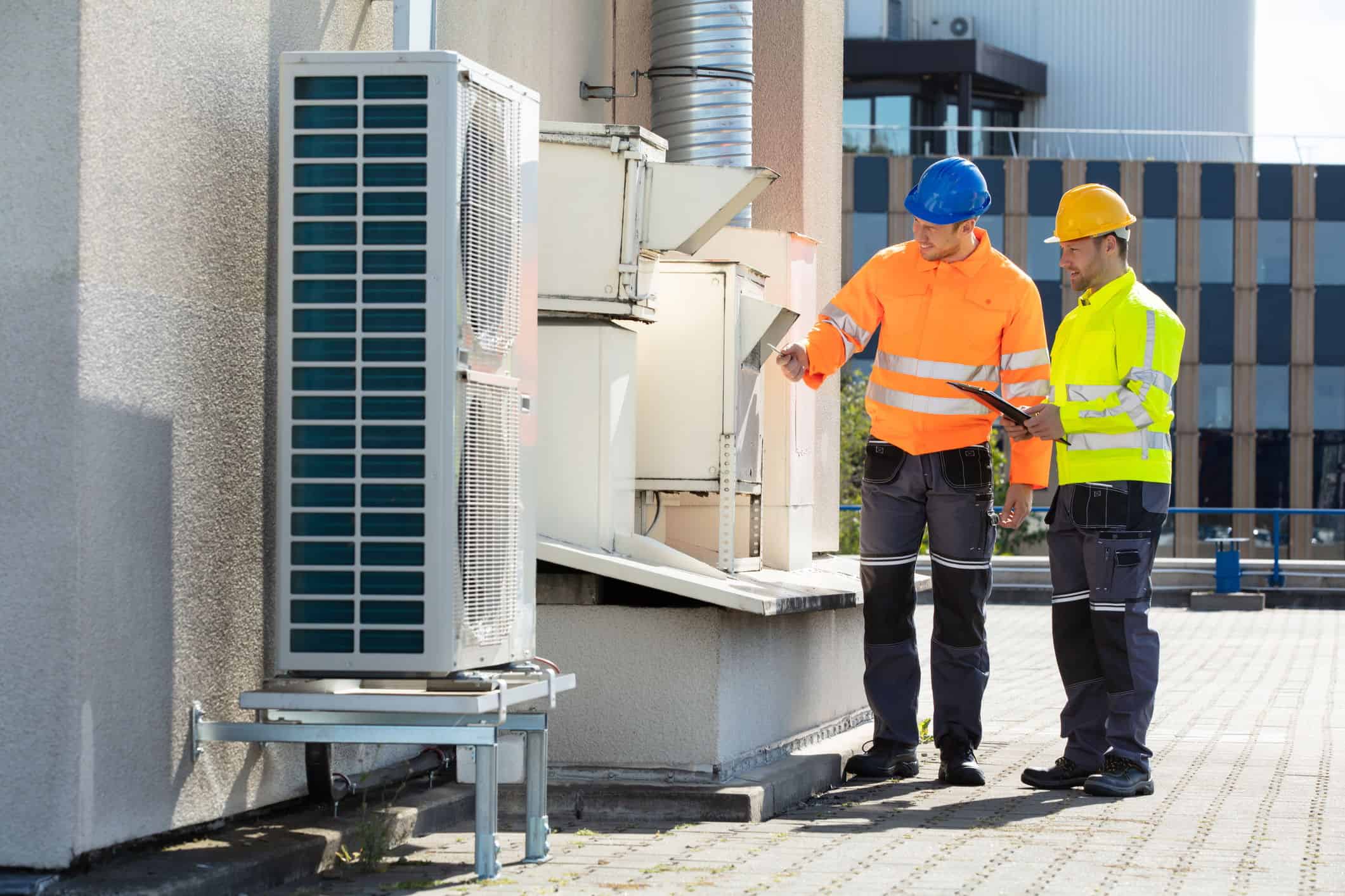 seattle heating cooling seattle Mini Split System Installation What to Expect When Installing a Mini Split System - Seattle Heating & Cooling two men looking at a mini-split system on an apartment roof.
