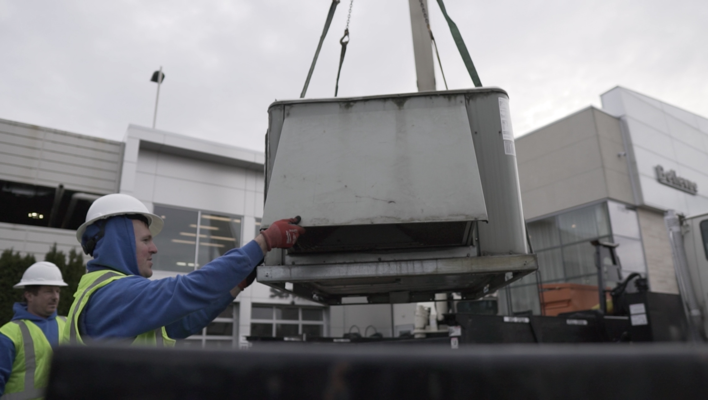 Our professional technicians are lowering down a new commercial AC unit.