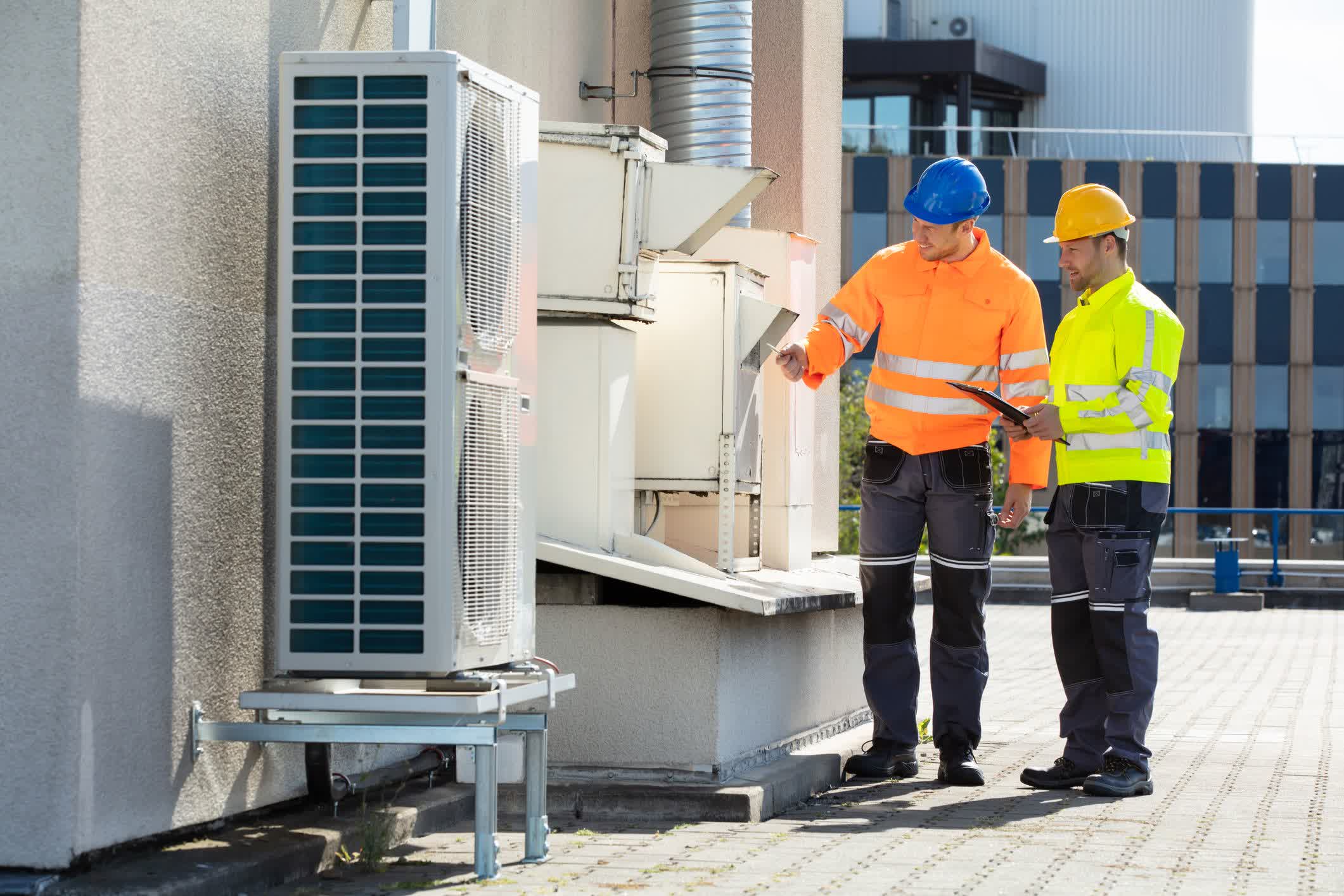 seattle heating cooling newcastle day and night american standard - Seattle Heating & Cooling Two HVAC technicians in safety gear inspect a rooftop commercial HVAC unit on a modern building under sunny conditions.