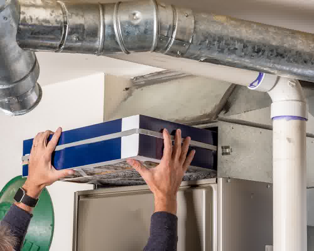 An HVAC pro checking an air filter to see the state of an air conditioning duct.